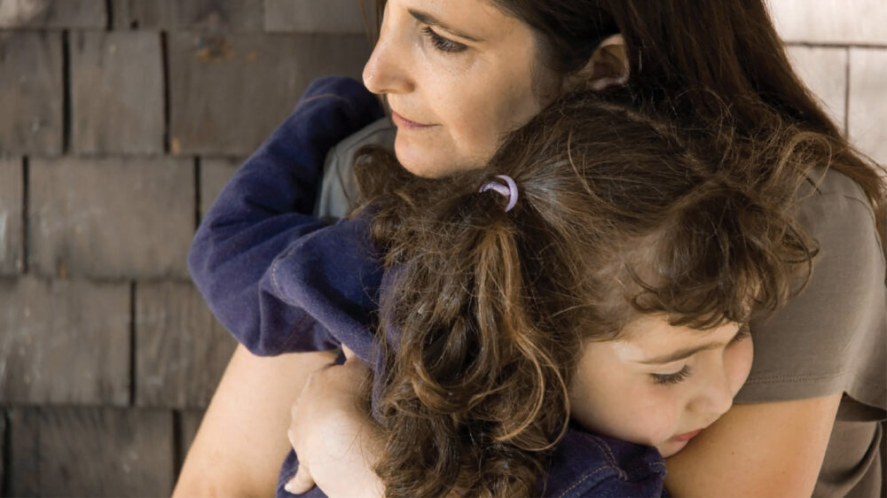 A mother embracing her toddler daughter.